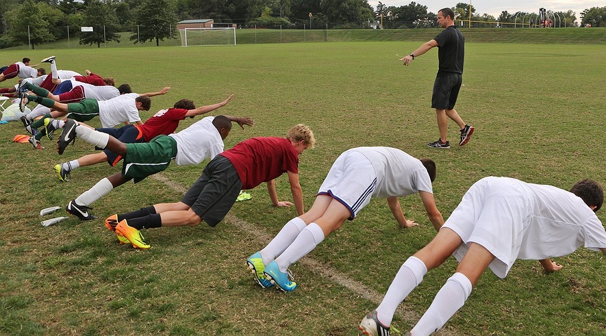 Trainer Eric Lay watches as the junior varsity soccer team goes through conditioning drills at school in Ladue, Mo., on Oct. 2, 2013.