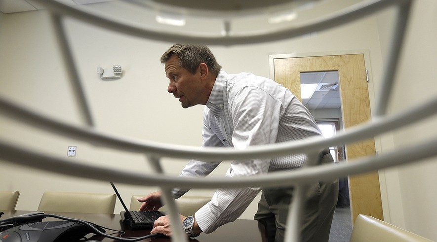 Kevin Guskiewicz, professor and former chair of the Department of Exercise and Sports Medicine at the College of Arts and Sciences, is framed by a football helmet at the University of North Carolina College of Arts and Sciences in Chapel Hill, North Carolina, May 13, 2015.