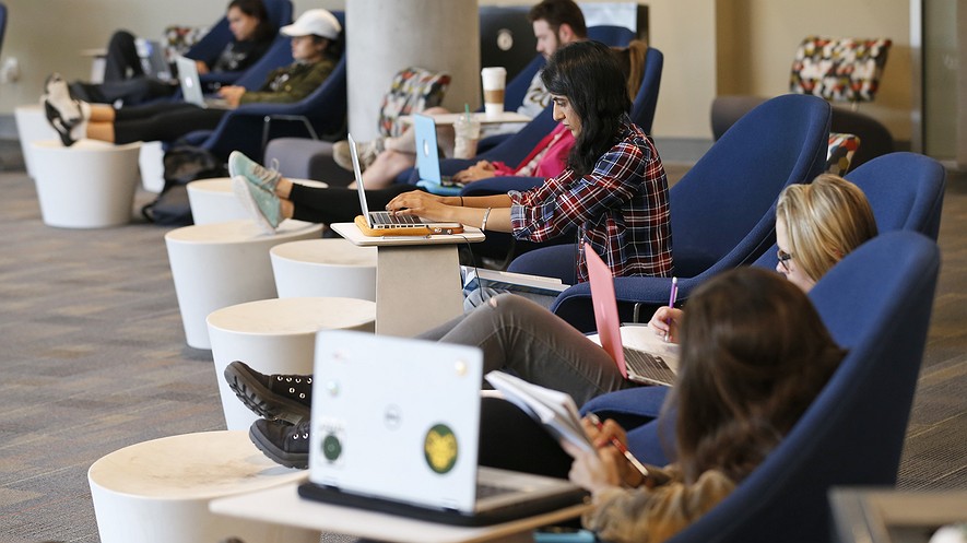 Los estudiantes se sientan mirando hacia el campus mientras trabajan en sus computadoras en la biblioteca renovada James Branch Cabell Library en el campus de la universidad de Virginia Commonwealth University en Richmond, Virginia.